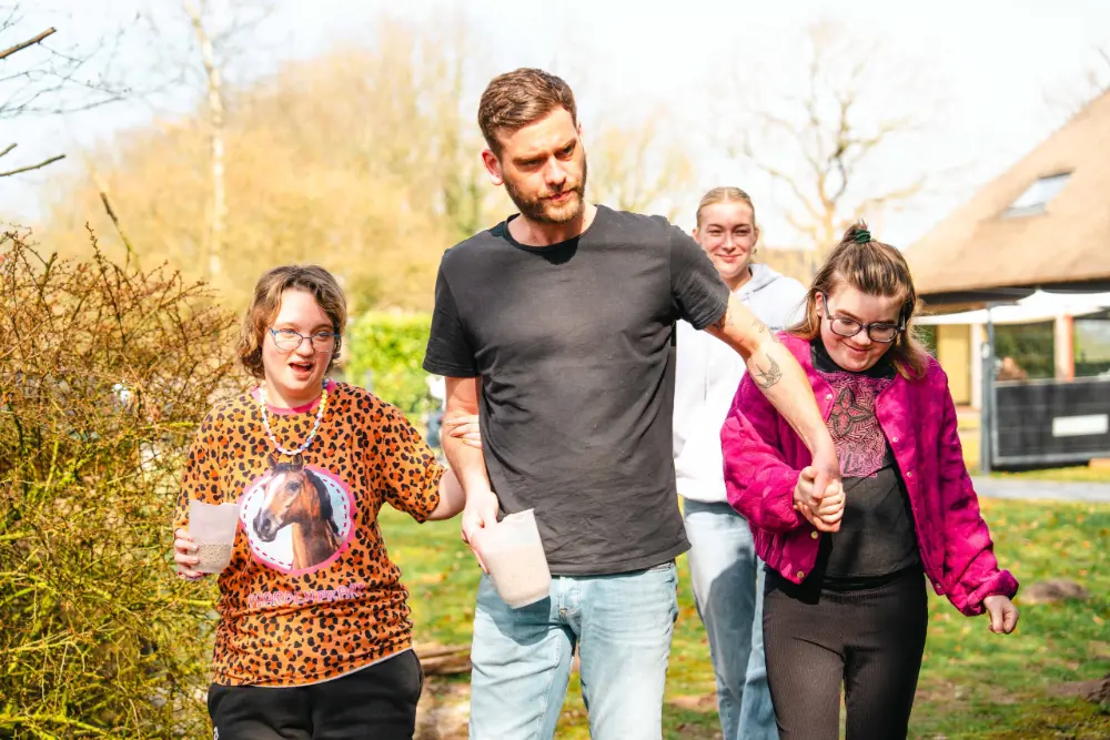 Bewoners en begeleiders wandelen lachend door het groen bij de boerderij in Roderesch