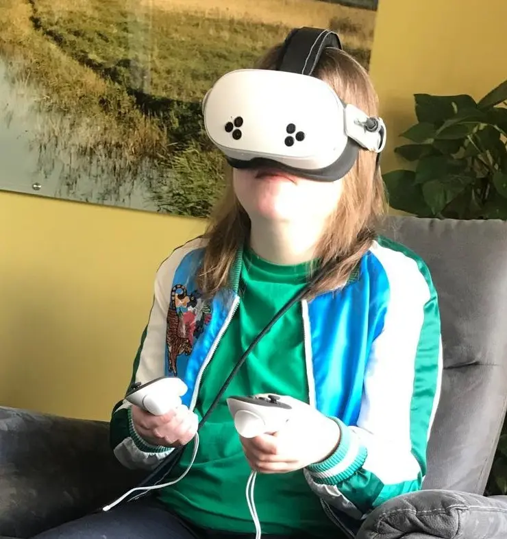 Een bewoner met een VR-bril op en controllers in de hand tijdens een behandelsessie