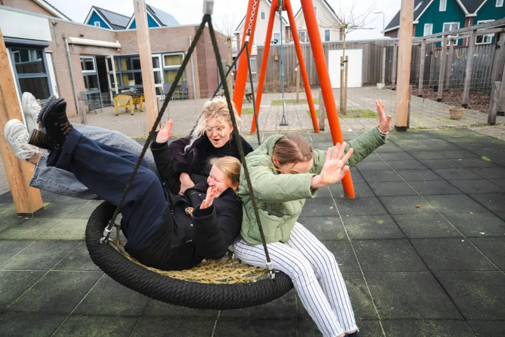 Bewoner en begeleider op de nestschommel in de tuin van Koninginnenpage in Wolvega